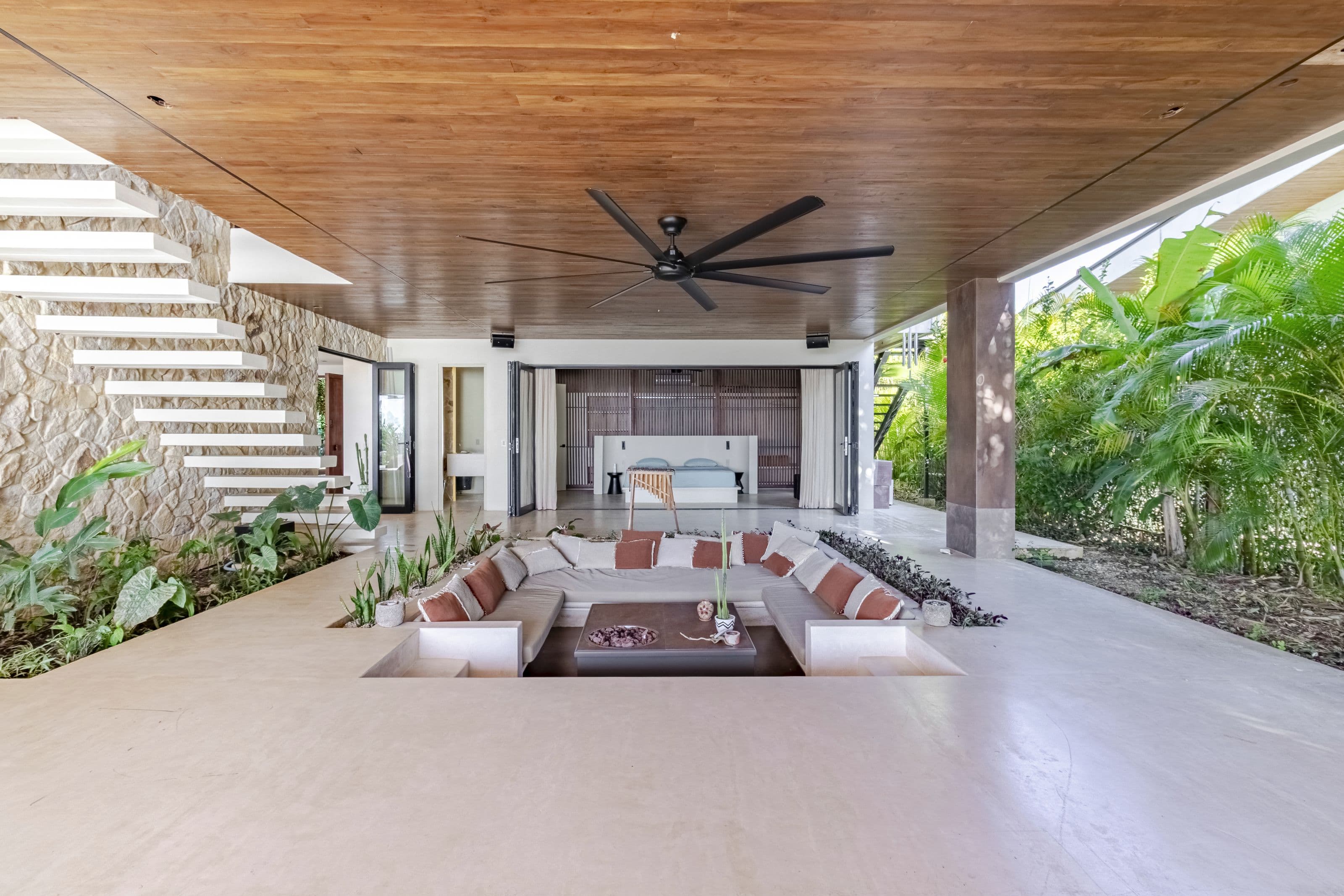 Wide view of the covered terrace and sunken lounge with a king bedroom beyond