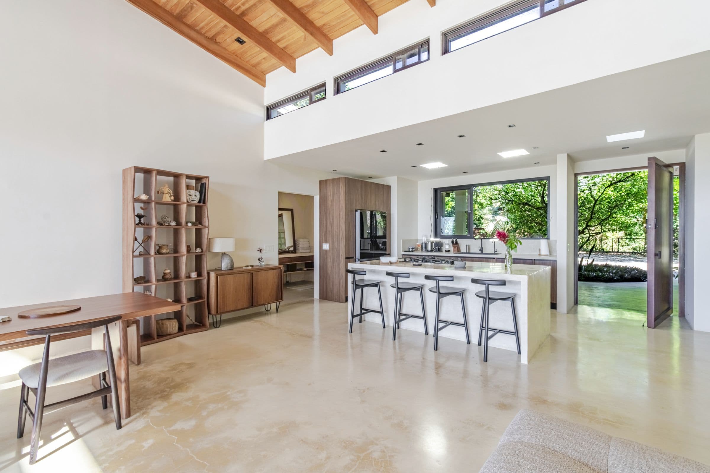 Kitchen island with bar stools beside the long wooden dining table