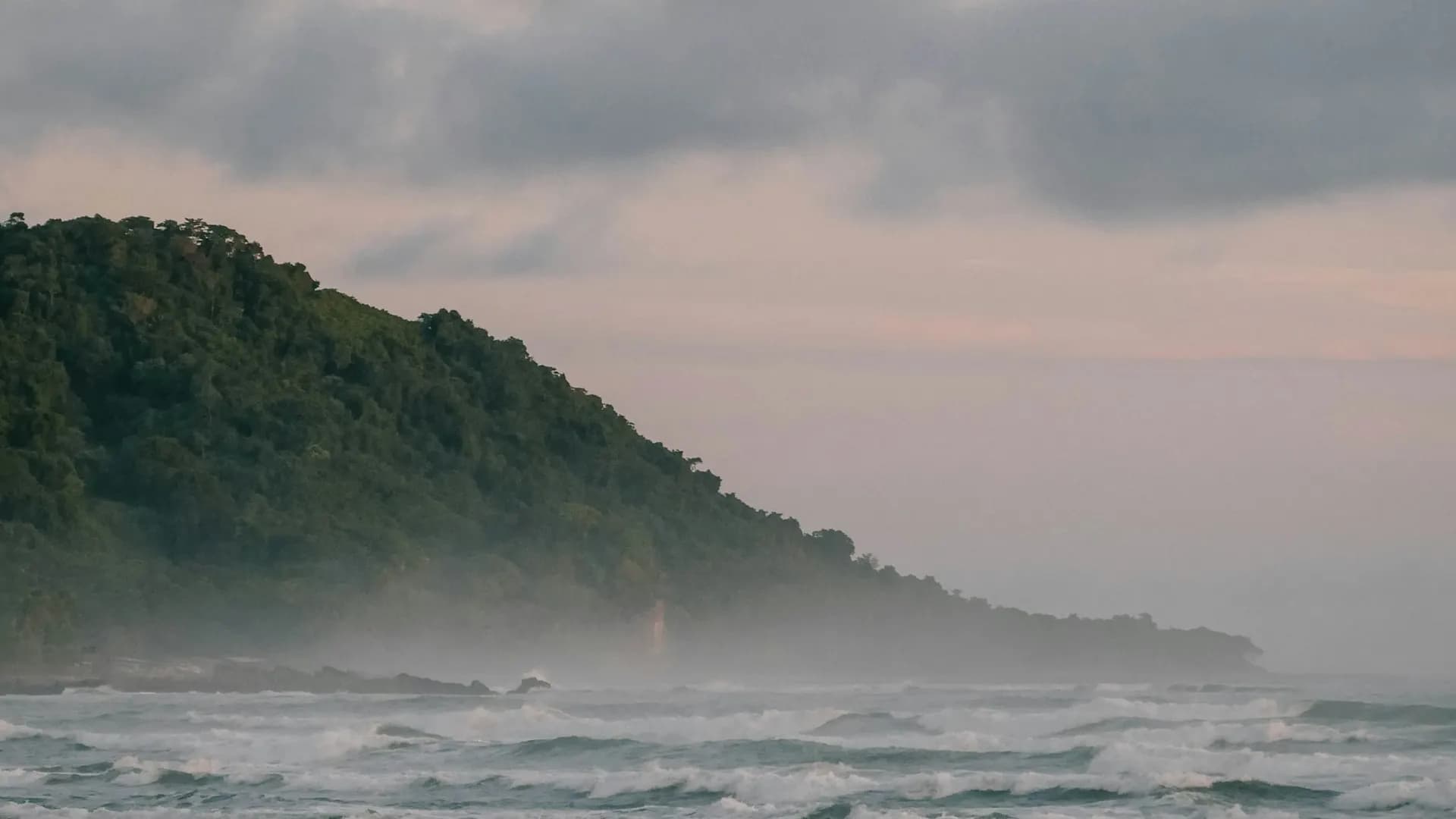 Waves roll toward a beach beneath low clouds in Santa Teresa.