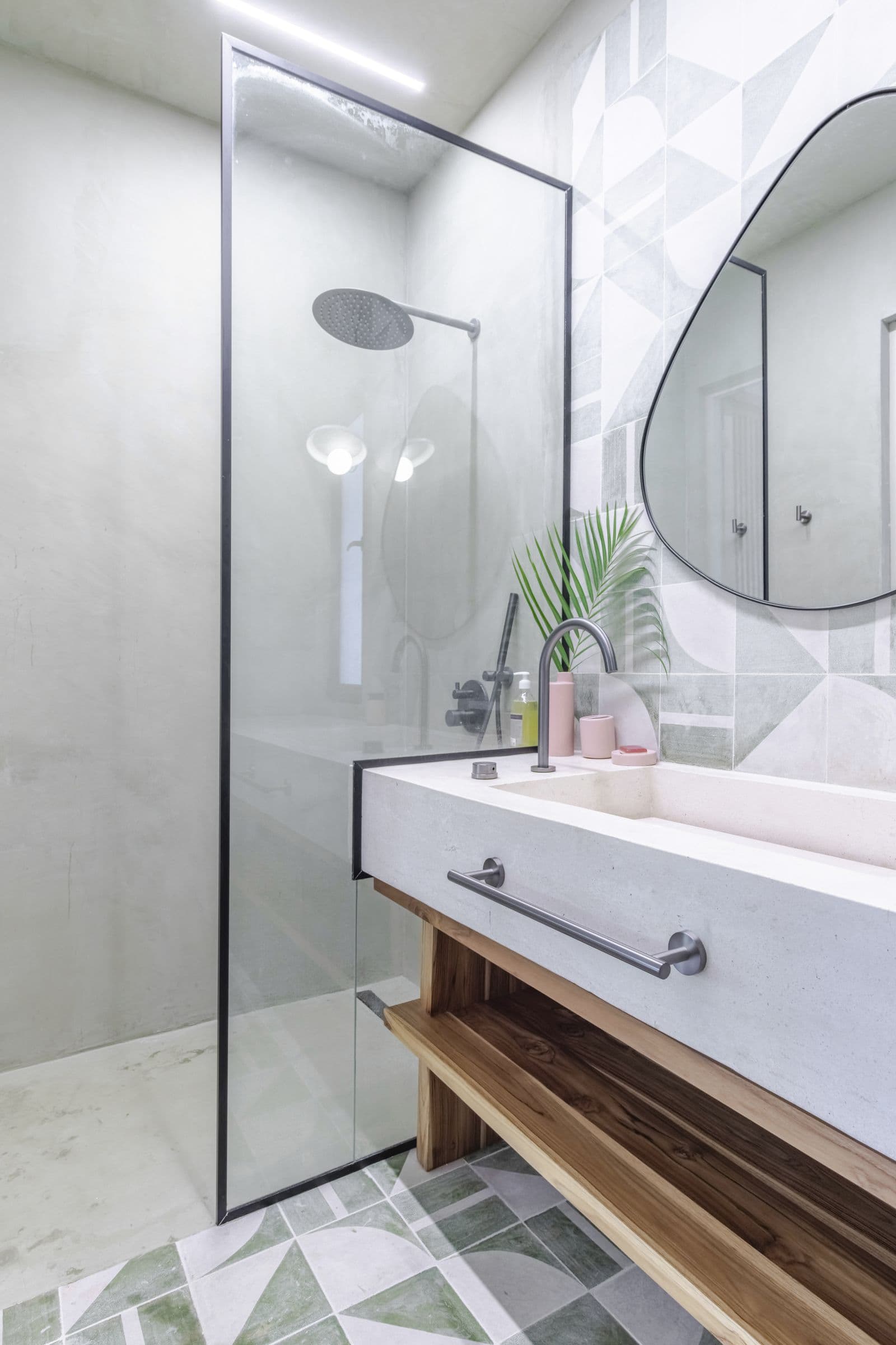 Glass-screened rain shower beside the basin counter, with patterned green tiles