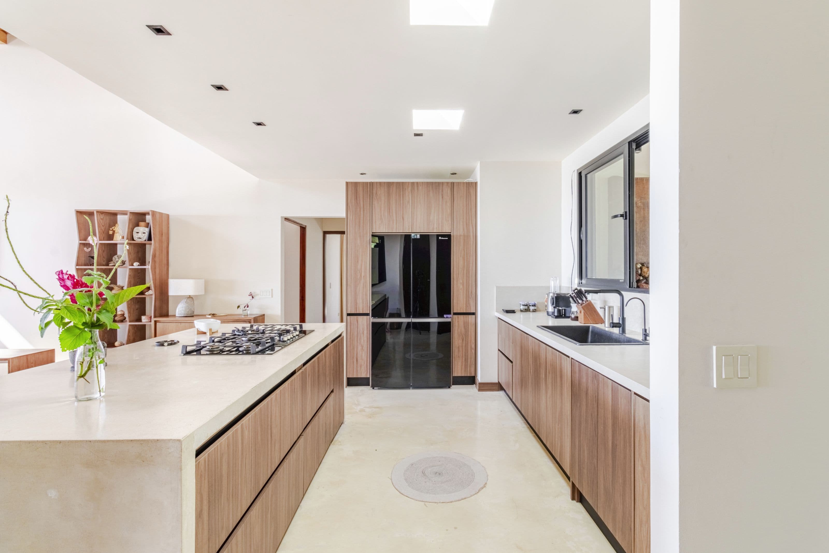 Kitchen with wood cabinetry, pale counters, gas cooktop and black refrigerator