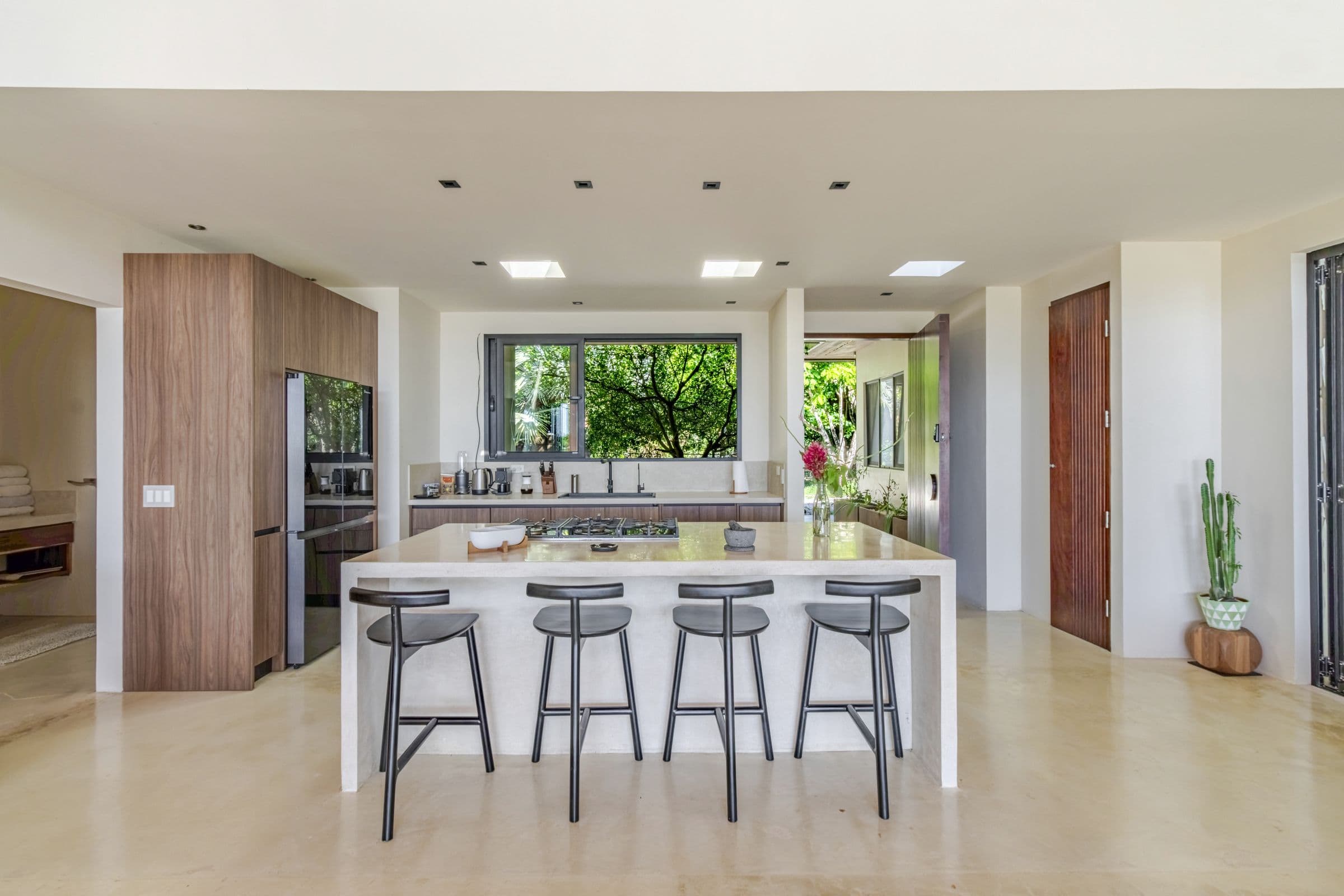Kitchen with a white waterfall island, four bar stools and a garden window