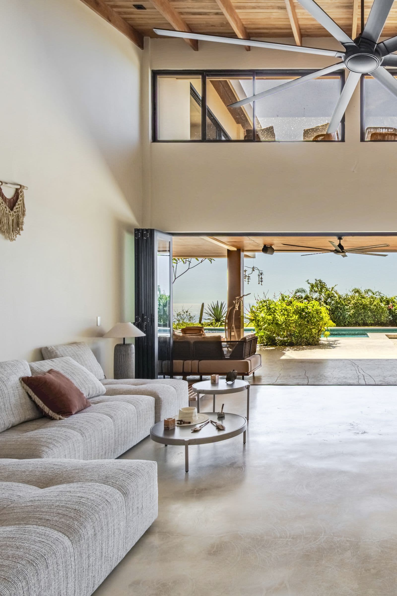 Double-height living room opening onto the covered terrace, pool and ocean view