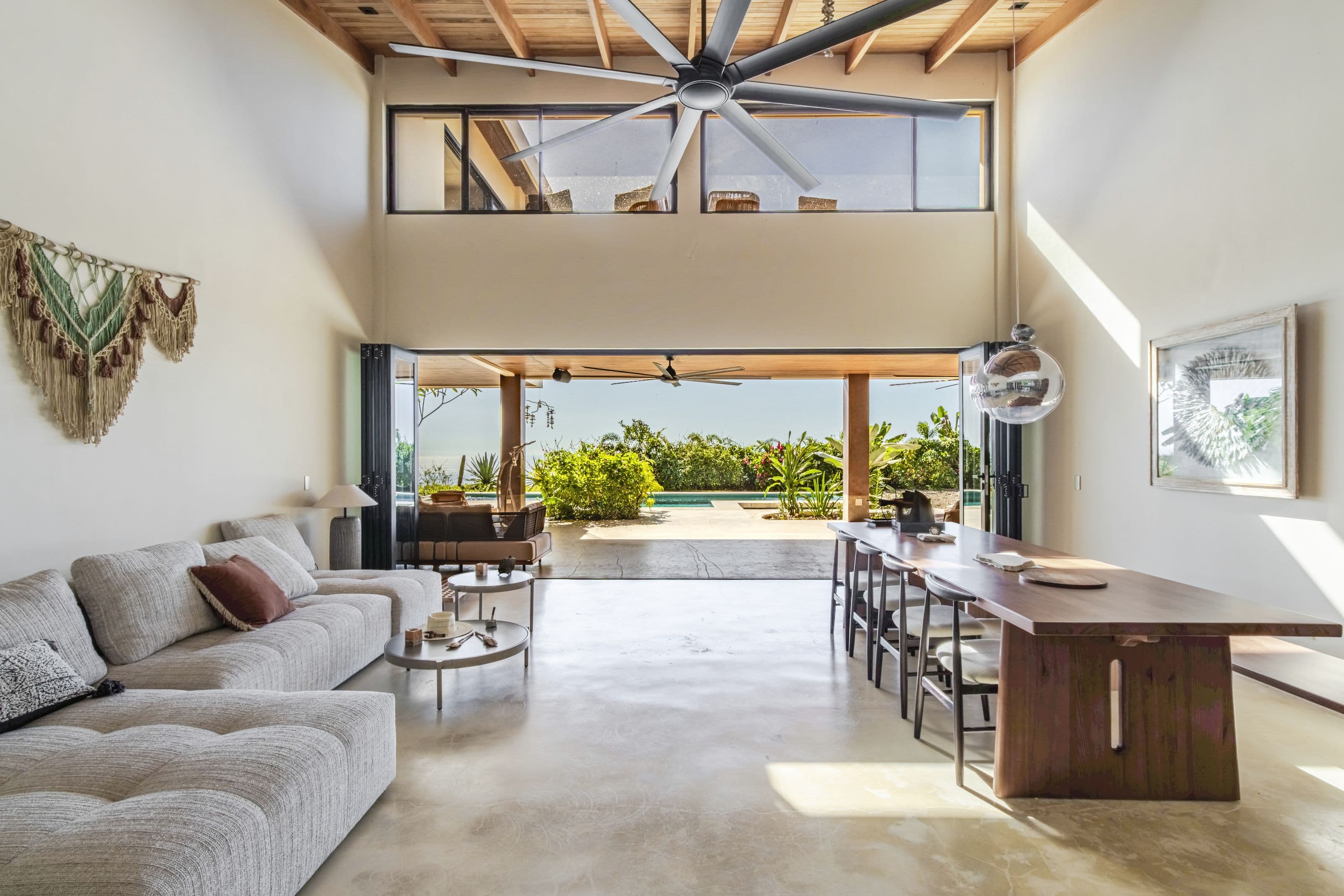 Double-height living room opening onto the covered terrace, pool and ocean view