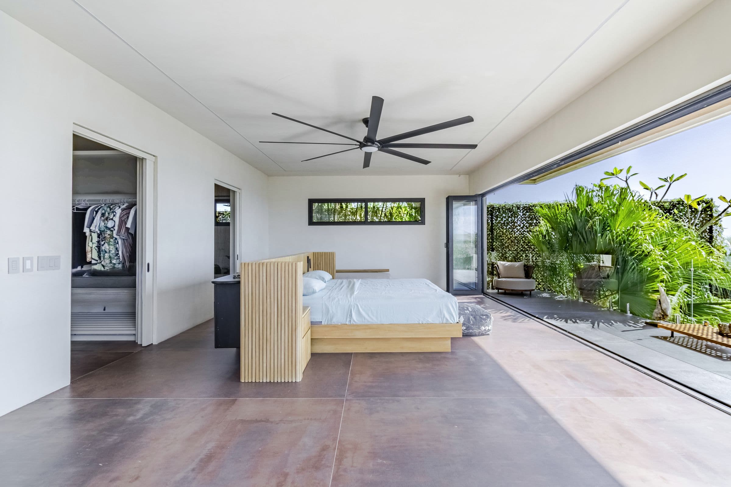 Upper-floor bedroom with a king bed, slatted wood headboard wall and open dressing area