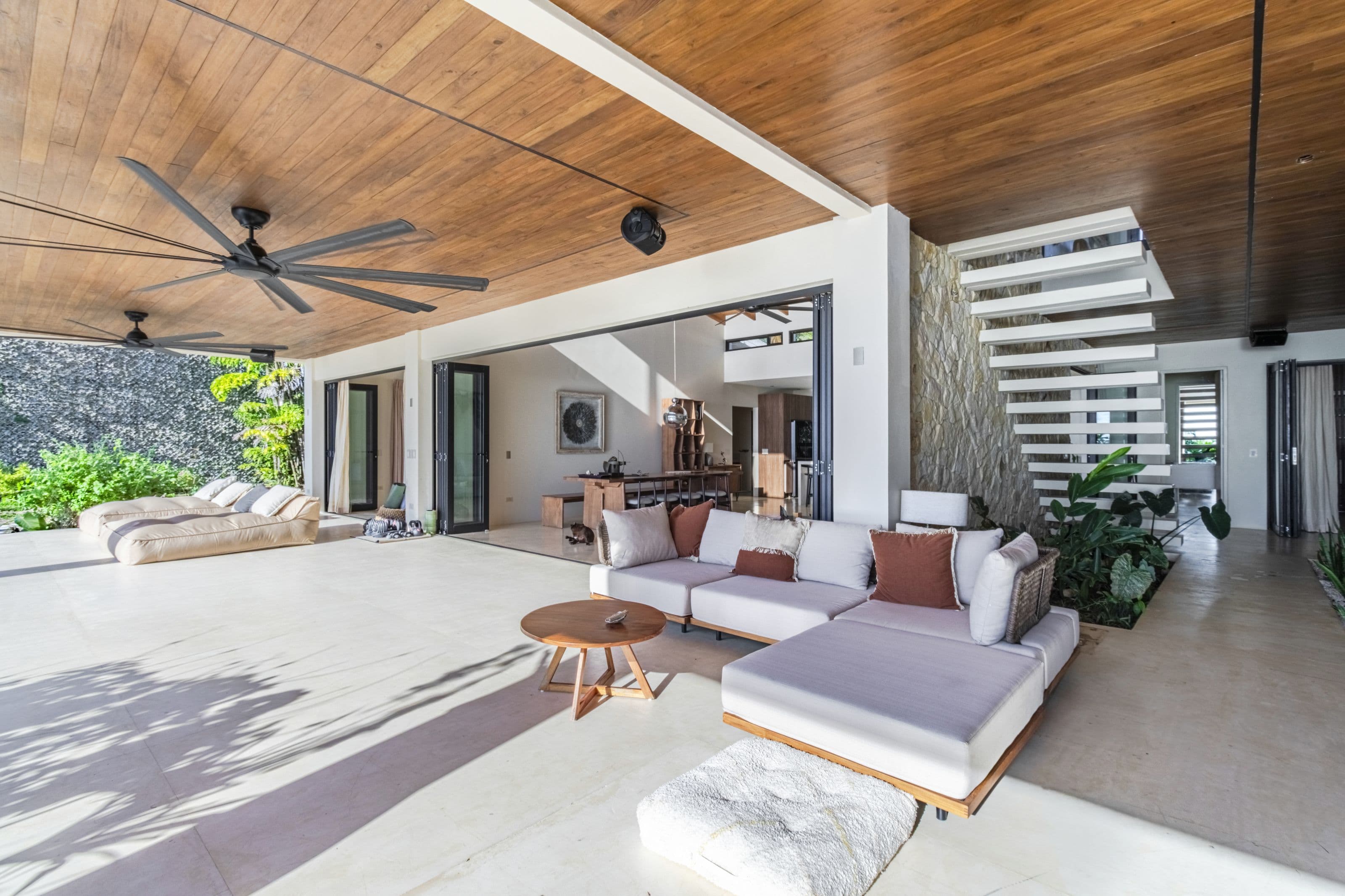 Outdoor living room with a white sectional sofa beneath the timber-clad terrace ceiling