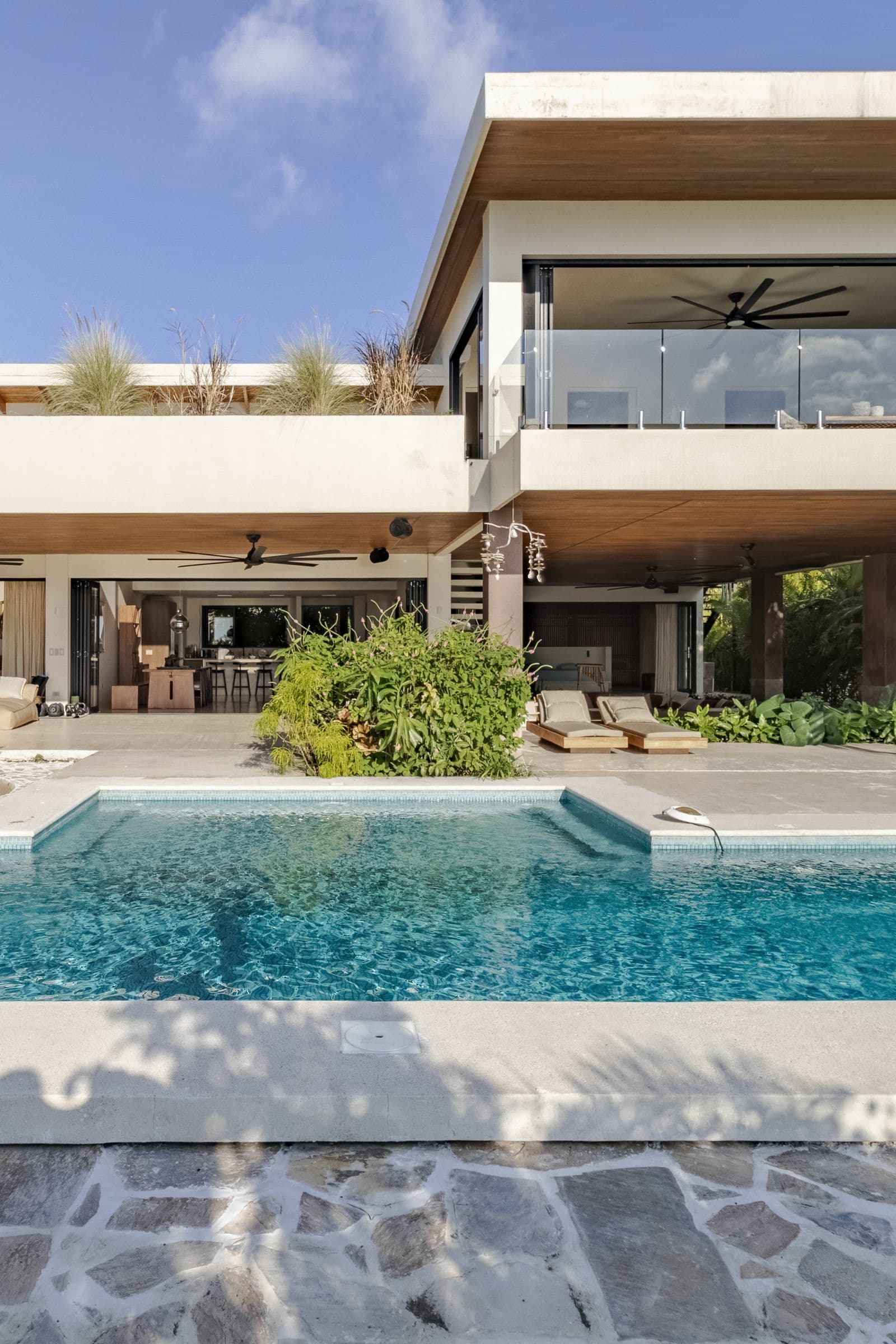 Turquoise swimming pool in front of the modern two-level villa, framed by tropical plants
