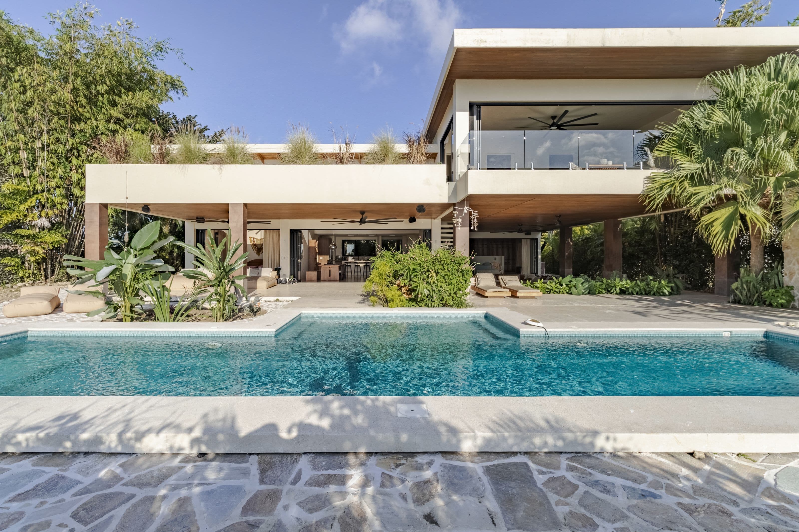 Turquoise swimming pool in front of the modern two-level villa, framed by tropical plants