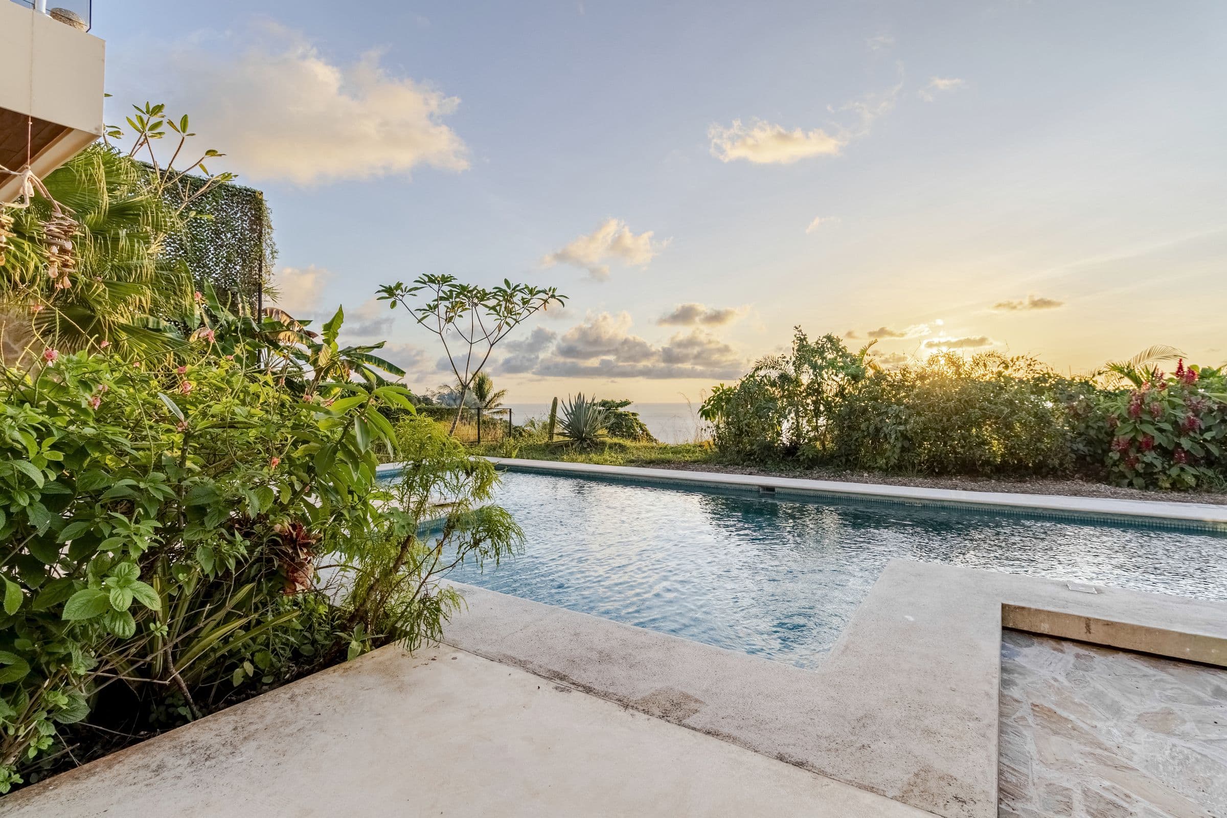 Swimming pool at sunset with the Pacific Ocean on the horizon