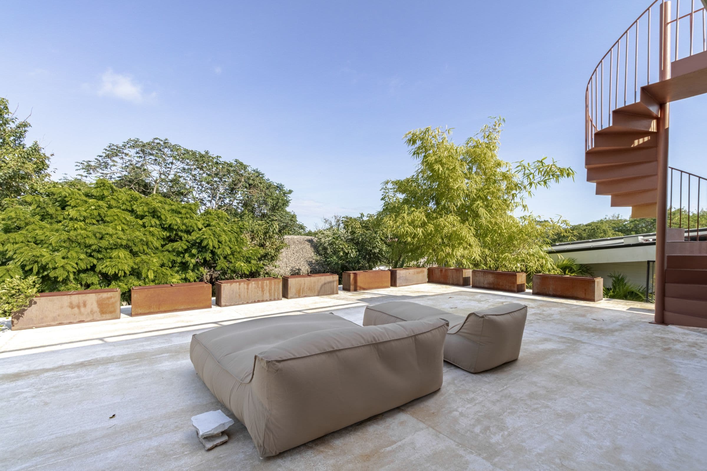 Roof terrace with oversized lounge cushions, planters and a spiral staircase