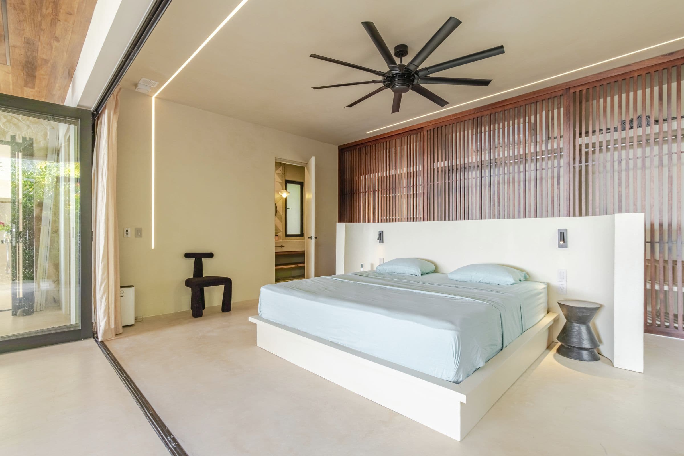 King bedroom with soft cove lighting and a sculptural chair