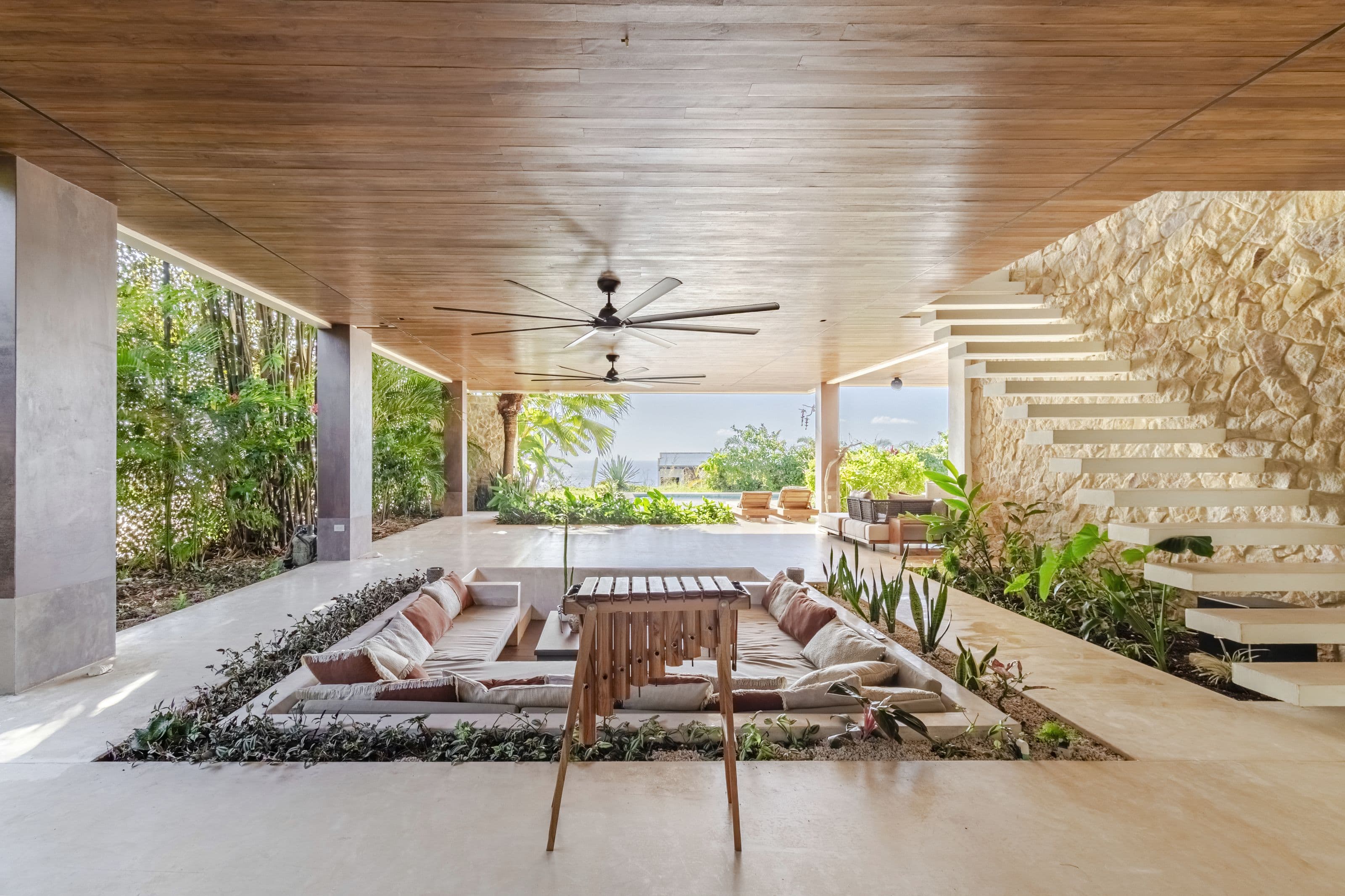 Covered terrace with a sunken lounge set into a planted garden bed beside a floating staircase