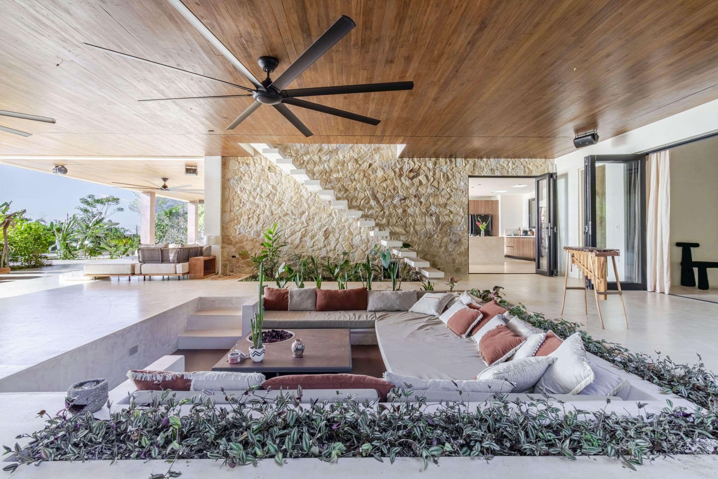 Sunken lounge beside a stacked-stone wall and floating staircase