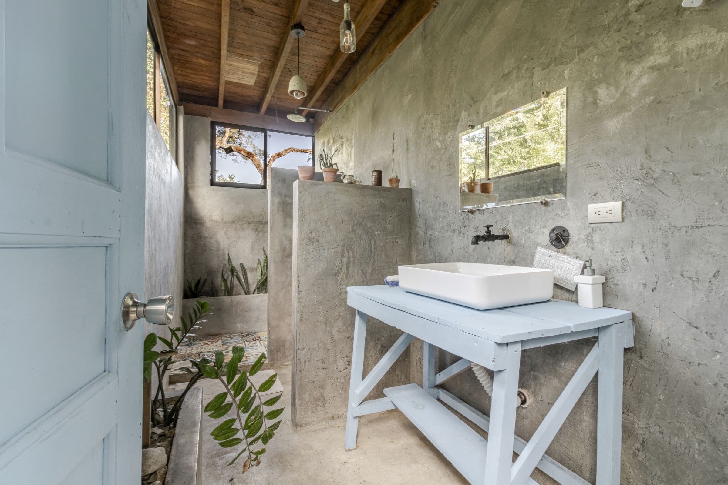 Surf Shack bathroom with a pale-blue wooden washstand, a vessel sink and textured grey walls under a timber ceiling