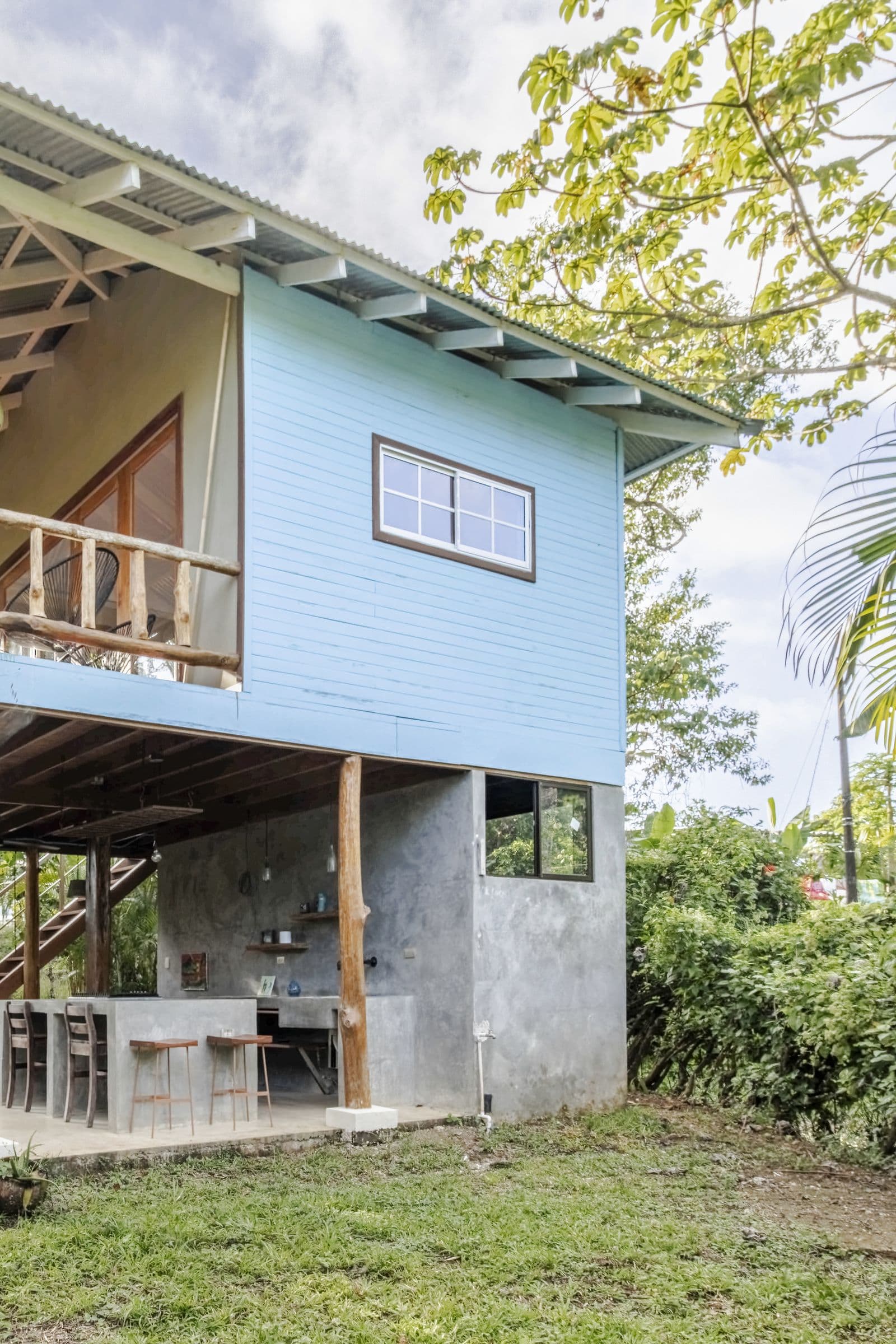 The Surf Shack, a pale-blue stilted guest house with a balcony, set in the jungle garden