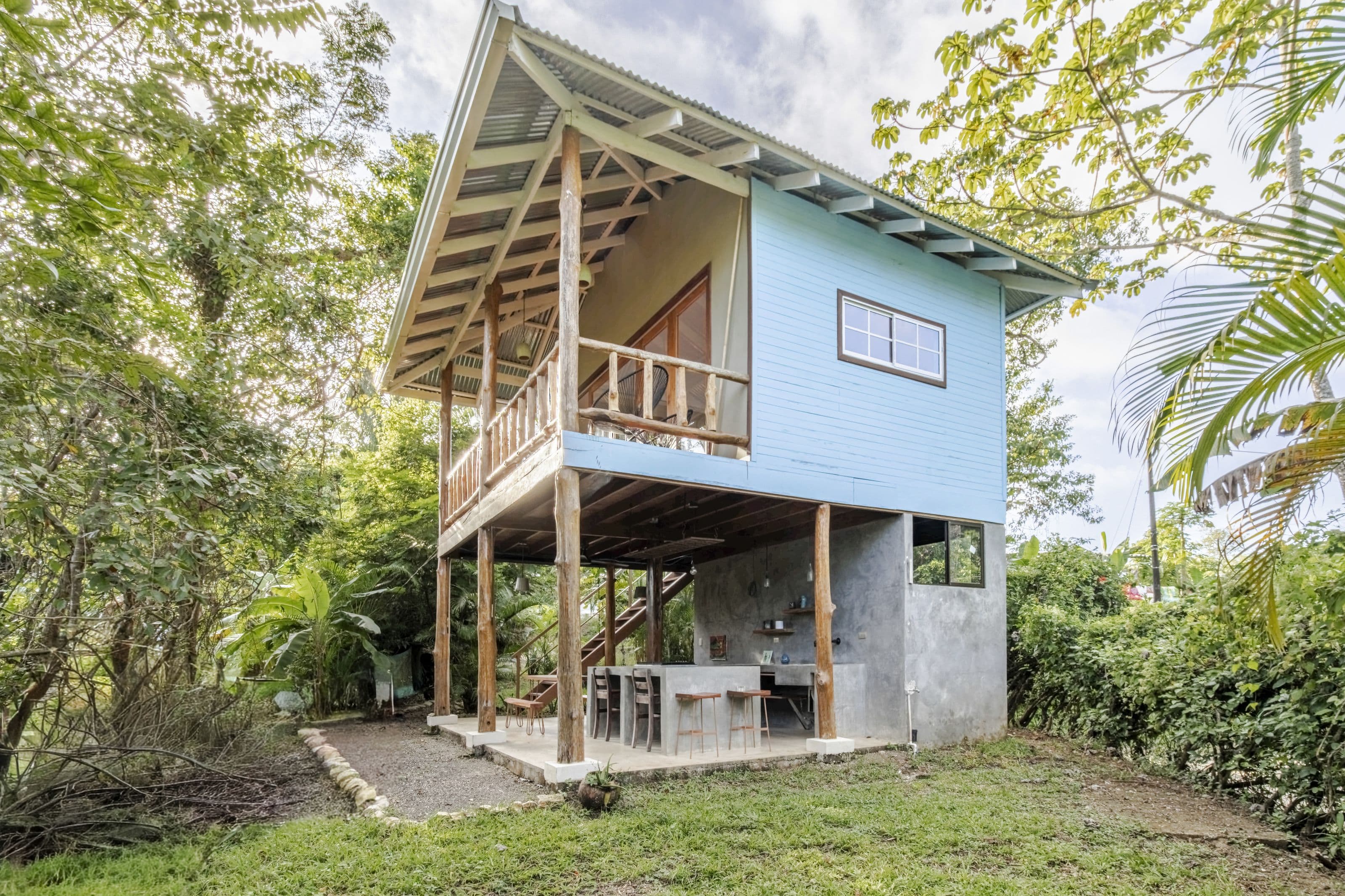 The Surf Shack, a pale-blue stilted guest house with a balcony, set in the jungle garden