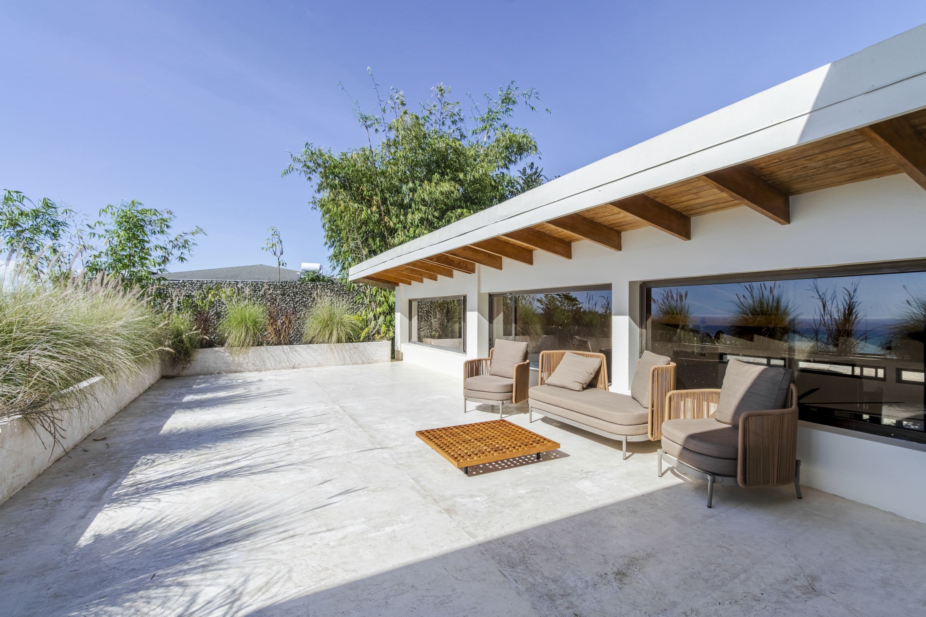 Sunny upper-level terrace with lounge chairs and a glimpse of the ocean