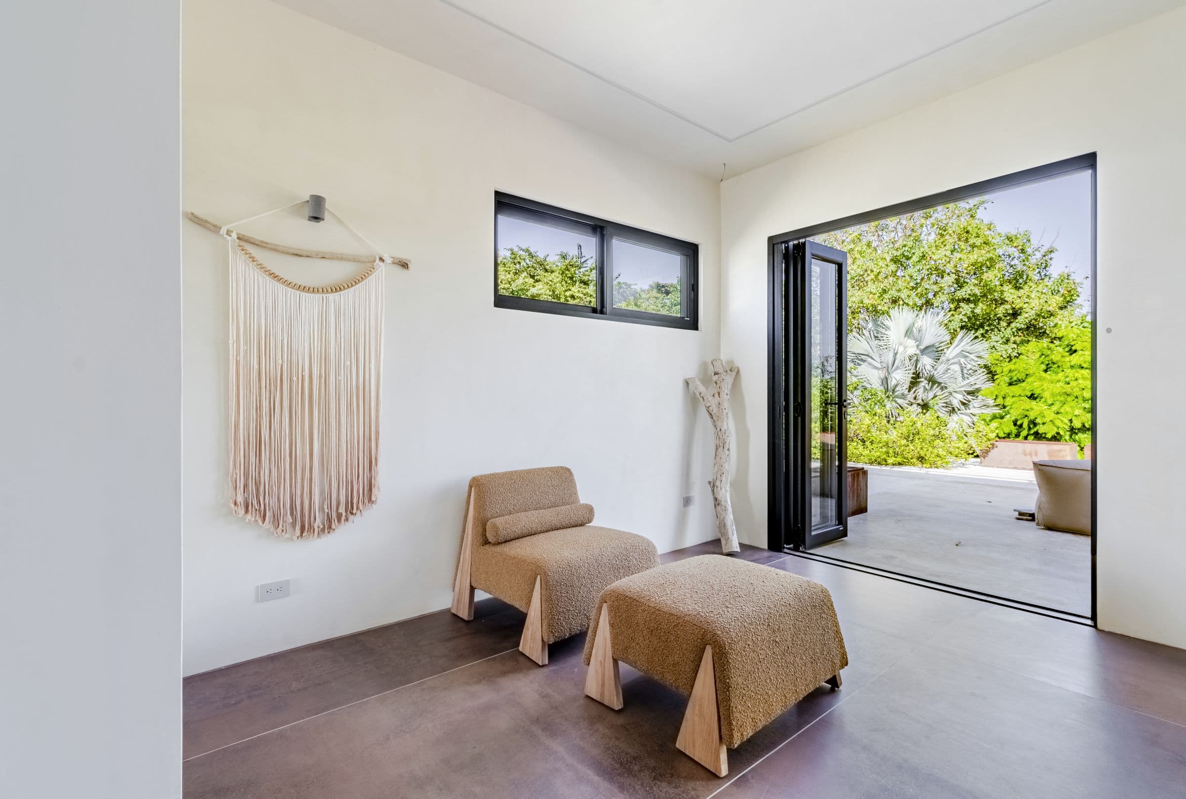 Reading nook with a lounge chair, ottoman and macramé wall art opening to the roof terrace